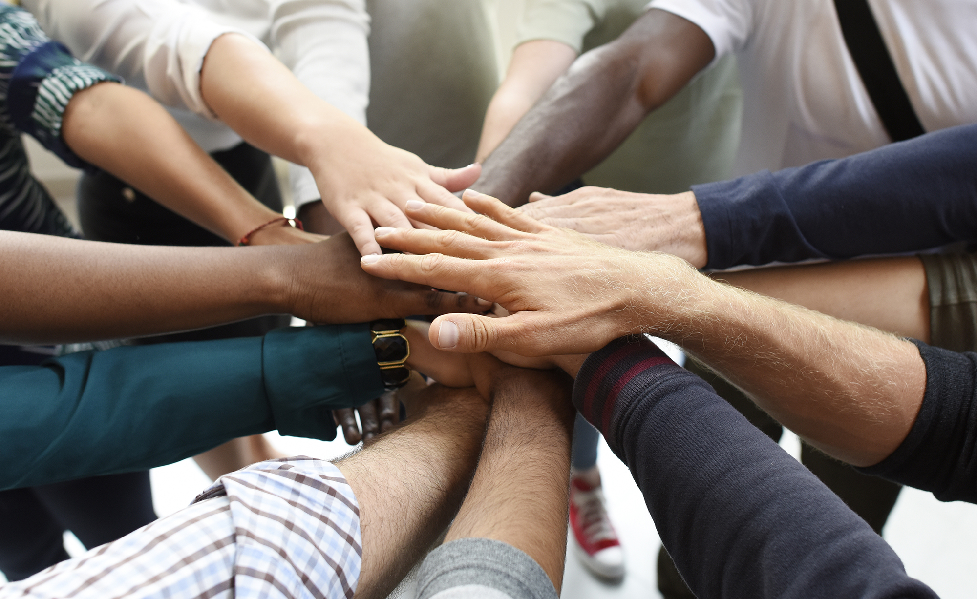 Many different people with their hands together in the middle